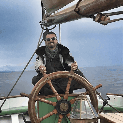 Ashden team member, Simon Brammer smiling behind a sailing helm