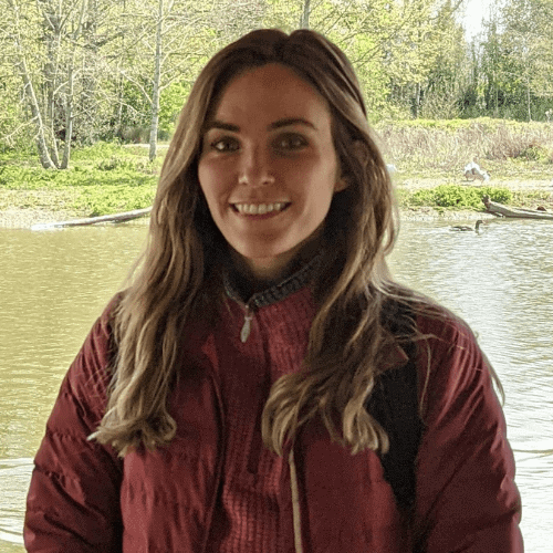 Ashden team member, Emma Seery smiling with a pond behind her