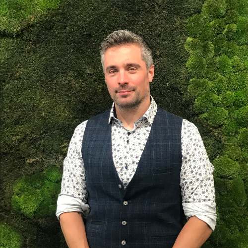 Ashden team member, Stephen Hall wearing waistcoat with a moss wall behind him